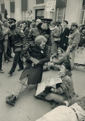 University Ave. scuffle: A policeman drags away one of more than 1,000 protestors who staged a sit-in yesterday outside the American consulate. The si(...)