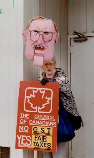 GST-Busters: Barbara Janes waves an effigy of Finance Minister Michael Wilson yesterday at a protest against the proposed goods and services tax outside his west-end constituency office