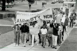 Amnesty wanted: A group of about 75 demonstrators march to Queen's Park yesterday, demanding that politicians grant amnesty to refugees, some of them who have been waiting as long as seven years