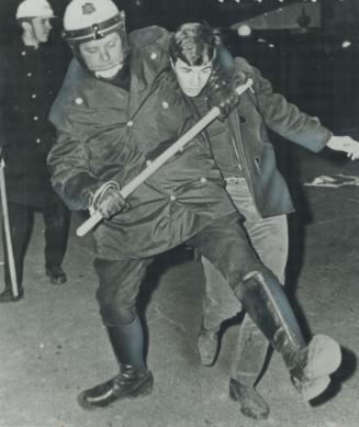 Clamped In A Headlock by a Montreal policeman who uses a threefoot riot baton to reinforce his grip, a demonstrator is hauled away last night during p(...)
