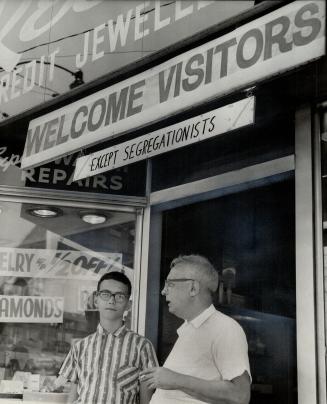 No racists wanted, Bay St. jeweller Charles Wolman and son David stand under anti-segregation sign they erected as expression of sympathy for Negroes