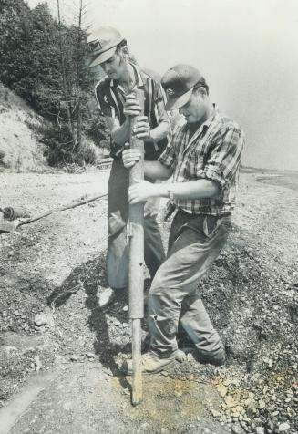 Farmer Bud Elliott (right), whose land borders the nuclear dump used by a refining firm at Port Granby, gets help from David Imlach in setting a fence(...)