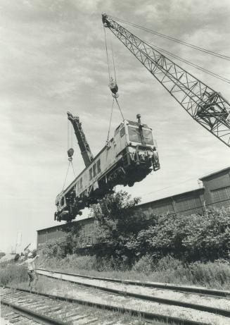 Up, up and away!, Two cranes lift a 94-ton track tamping machine from the yard of Canron Inc