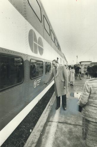 Emptying his pipe before boarding the GO train at Oakville today for the inaugural ride on the first of 80 bi-level cars is Transportation Minister Ja(...)
