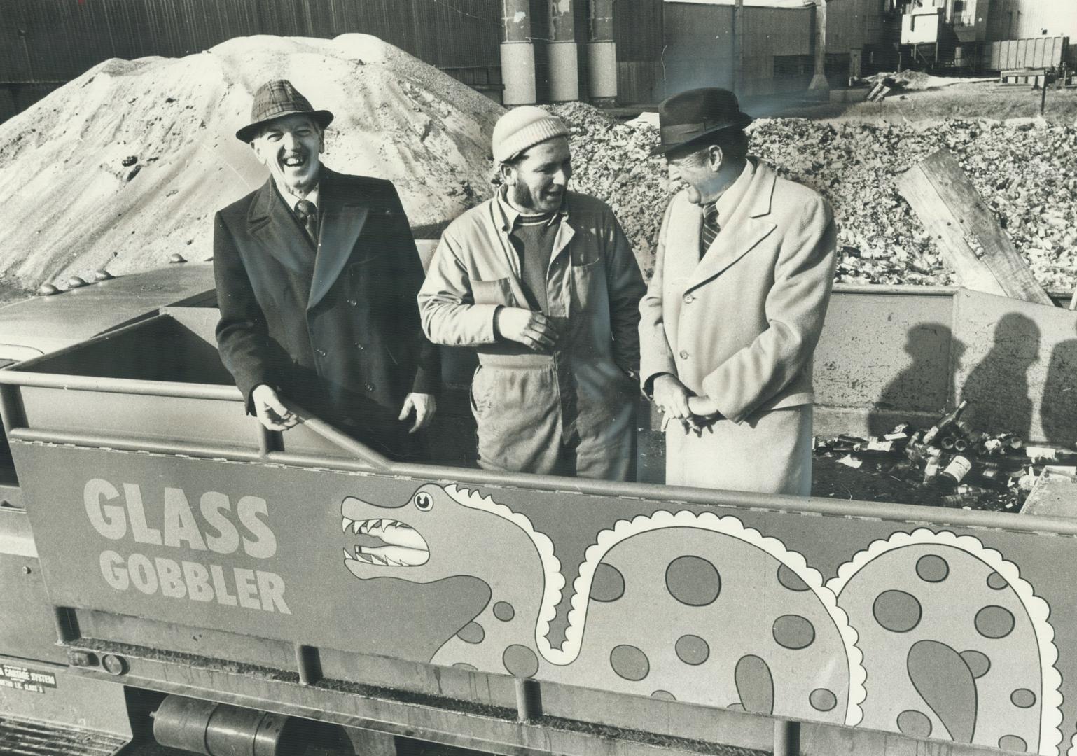 Three men in the truck are pointing to the name on the side, Glass Gobbler, which defines its job