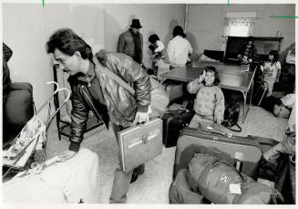 Gathering gear: A refugee gathers up his family's luggage from the recreation room of the shelter where they have been staying to move in with a Buffalo family
