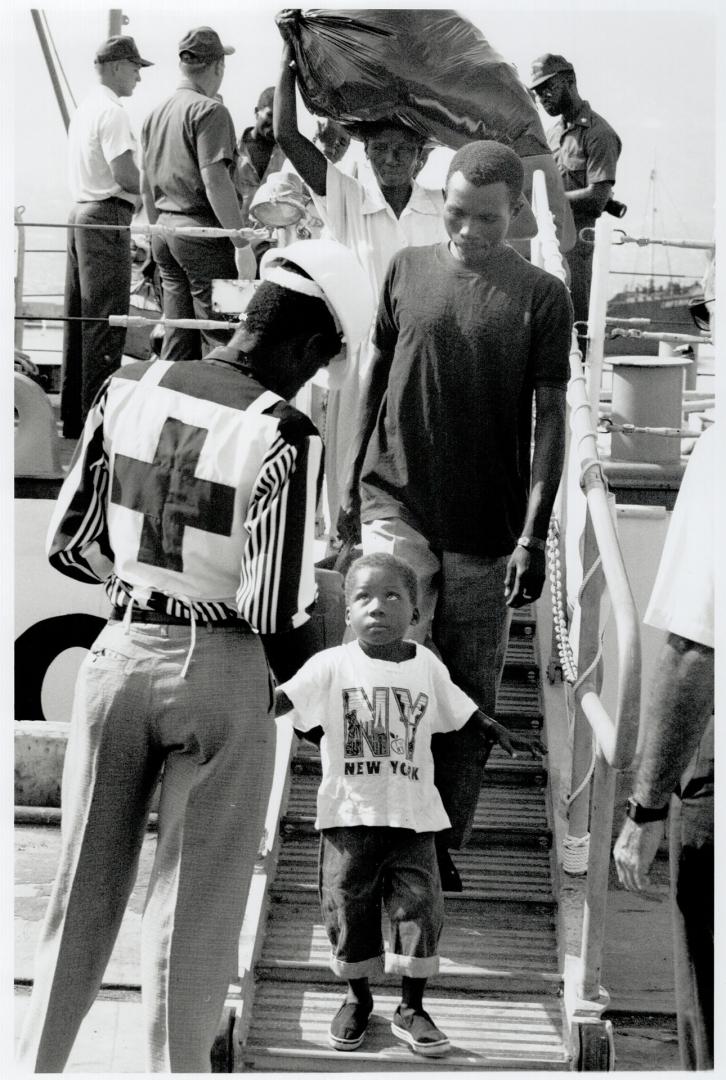 Many of the returnees wear U.S. paraphernalia, like the boy below. Michelet-Joseph Pierre, far left, has gone into hiding