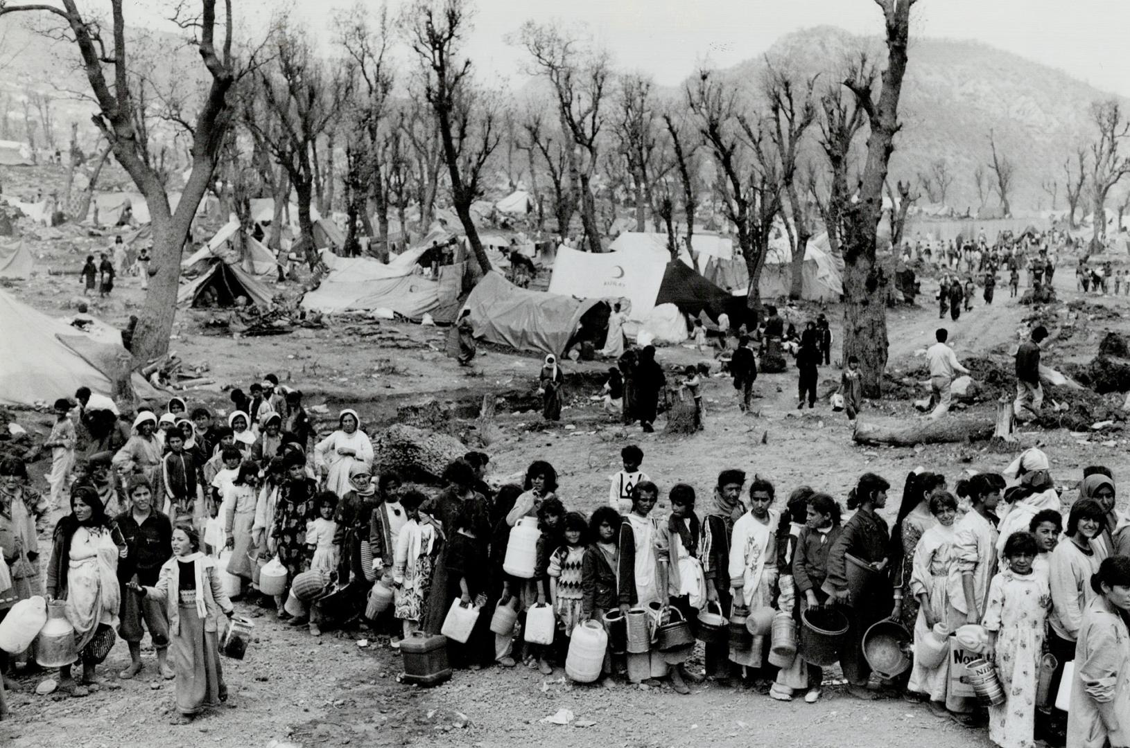 Rebulding time: Kurdish refugees, far left, line up for water at camp near Turkish border last year