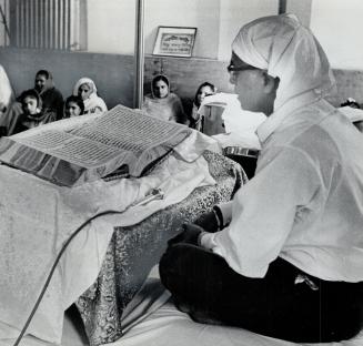 Temple member reads from sacred book, It contains teachings of Guru Nanak, Sikhism's founder