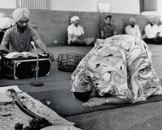 A woman prays before symbolic sword during sikh worship service, Money contributions are accepted but there are no collections as in other churches