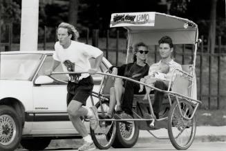 Easy money? Doug Bell, 22, pulls Danielle Henning, Jeff Kramer and baby, Jason, in a rickshaw on Seaton St