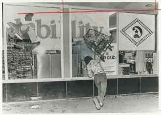 A young hooligan hurls a shopping cart through the window of a Bathurst store