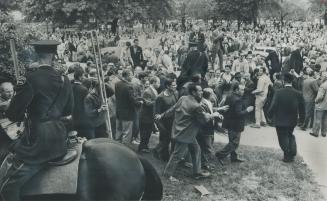 Mounted On Horseback, police move in to try to control the crowd, estimated at 4,000, running hysterically about in Allan Gardens. Shouts of kill, kil(...)