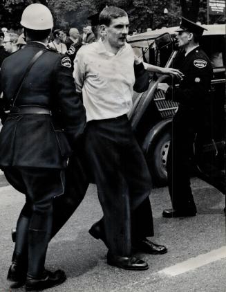 Battered and bleeding, William Beattie, leader of the Canadian Nazi Party, is led away from the mob which attacked him in Allan Gardens yesterday