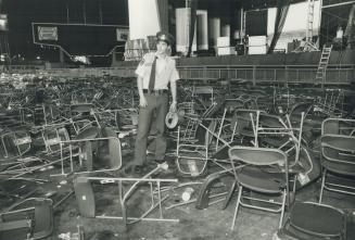 Security guard surveys wreckage left by rock fans at CNE Grandstand last night
