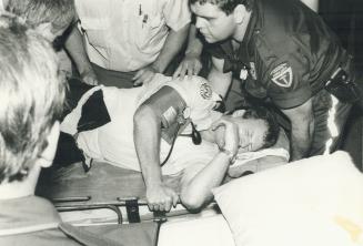 Detective Quintin Johnstone, shown in 1985 photo, is carried on stretcher after being stabbed at Caribana festival