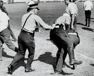 Scuffle starts: A policeman becomes entangled with an unruly fan during yesterday's soccer riot at Varsity Stadium and tries to wrestle him to the ground