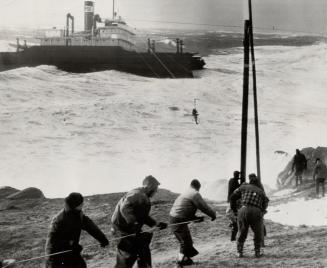 First of the crew of 31 is seen being rescued by coast guard breeches buoy as high winds and turbulent seas beat the stricken and battered collier Oak(...)