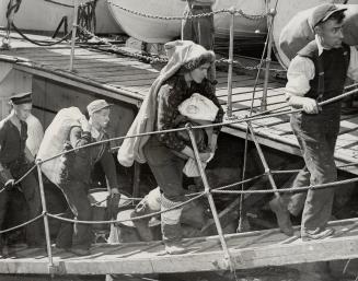 Crew of the Gallant Nascopie, which is now a broken vessel far in the northern reaches of Hudson Bay, are shown leaving the government icebreaker N. B(...)