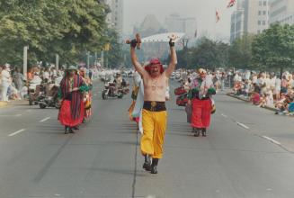 Cutting a swath through town, One of the 15,000 Shriners in colorful costumes marches down University Ave