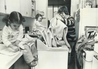 Nancy MacIldoon, a 26-year-old separated mother, gets a little help with the laundry from daughters Lisa, one, left, and Jennifer, 2. It's an uphill s(...)