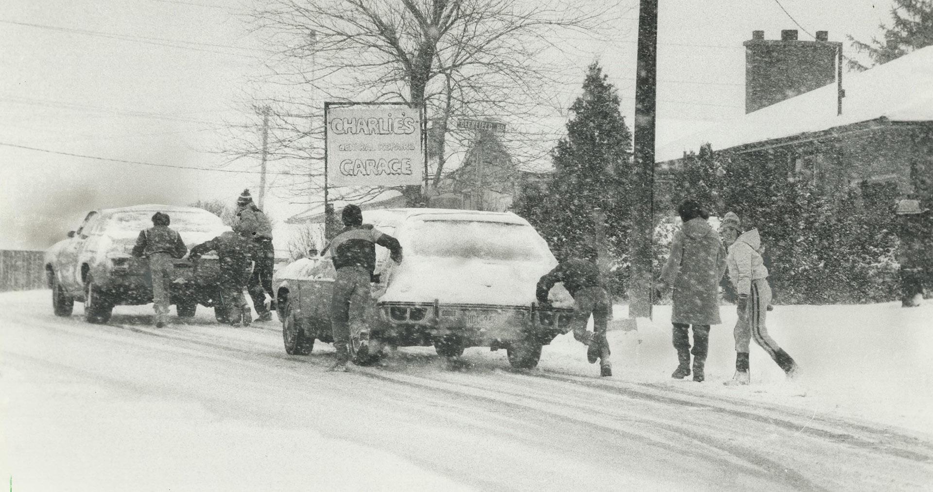Heave-ho! Students on their lunch hour from Donell School in Newmarket help cars up the hill in front of their school following yesterday's snowfall