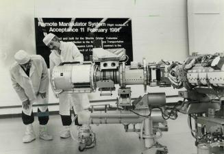 Space-bound. Tom Young (right) of Spar Aerospace explains workings of Canarm, $100-million Canadian-built remote manipulator system to go into U.S. sp(...)