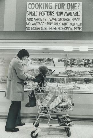 Mrs. John Macdonald and son Gregory, 3, in miracle mart, Sign indicating single portions of meat are on sale is seen in background