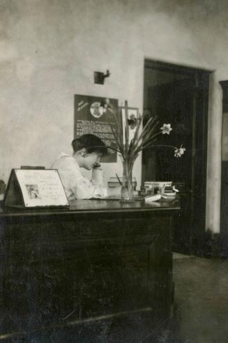 Image shows a person at the desk inside the library taking a phone call.