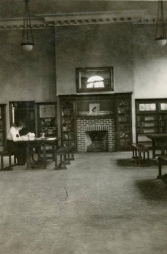 Image shows a person reading at the desk inside the library.