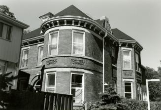 Image shows a part of a two storey house with some trees around it.