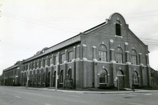 Image shows the front and the side of the long building along the street.