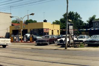 Image shows an auto repair shop with a number of cars parked beside it.