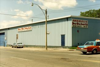 Image shows a small building with a few cars parked beside it.