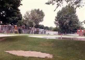 Image shows a playground with some trees in the background.