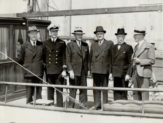 On the afterdeck of the Pathfinder, after the luxury yacht was taken over by the navy, stand Roy McPherson, Commander A