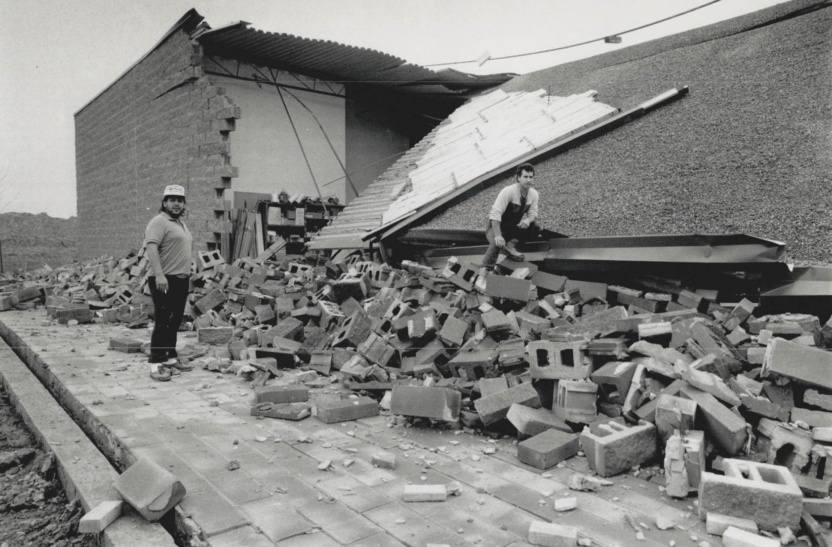 Storm Aftermath. Workmen survey the damage caused by high winds last Saturday when a block and brick wall of a unit under construction on Matheson Blv(...)