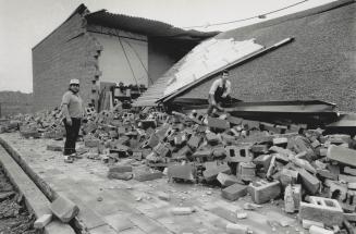Storm Aftermath. Workmen survey the damage caused by high winds last Saturday when a block and brick wall of a unit under construction on Matheson Blv(...)