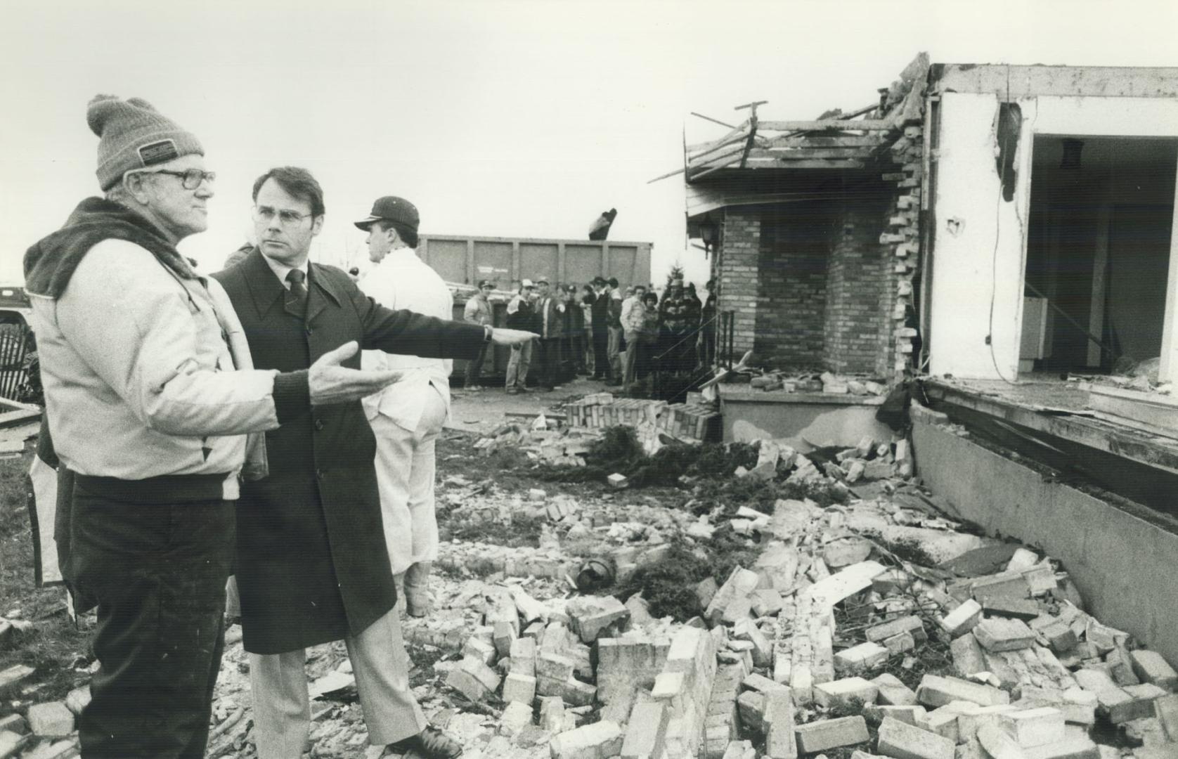 Photo of Min. Claude Bennett talking to John Van Der Wielen in front of Van Der Wielen's damaged home located in Reec s corn five people in his family lived there