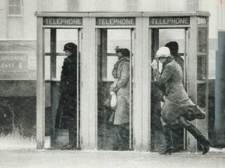 Huddling in phone booths, pedestrians take refuge today from blizzard that swept in from Illinois, paralyzing highways, Metro roads and streets. This (...)