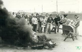 Auto workers picket in Oshawa, These striking General Motors' workers are all smiles as they gather around a bonfire of wood and tires they built on t(...)
