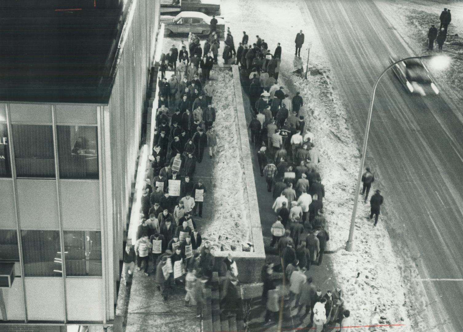 Pickets march is front of the strikebound Oshawa Times after a rally which endorsed continued defiance of an injunction limiting the number of pickets(...)