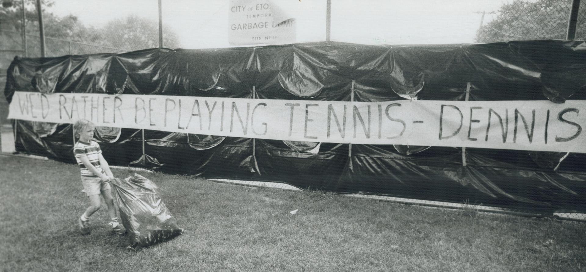 Jay Cleary, 8, drags a garbage bag to a temporary dump at a tennis court in Etobicoke - ignoring a giant message to Mayor Dennis Flynn