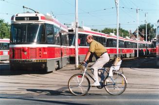 Going Nowhere: Cyclist pedals past idle TTC streetcars lined up in marshalling yard in Toronto's east end