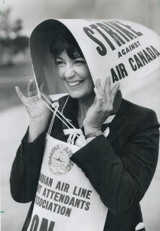 Keeping dry: Sheila Burns uses a picket sign to protect her from the rain yesterday as striking Air Canada flight attendants protested at Pearson International Airport