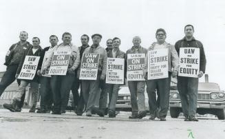 Five of eight signs held by workers during their strike last year at General Motors in Oshawa demand parity in pay with U.S. workers. The strikers wer(...)