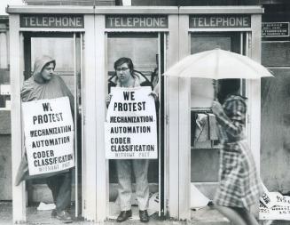 How to picket in the rain, Pickets Bernie Gorman (left) and Merton Ryan ducked into telephone booths to escape driving rain yesterday outside the post(...)