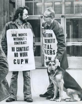 Striking postal workers, one of whom brought his dog along, talk on picket duty outside Terminal A at Front and Bay Sts