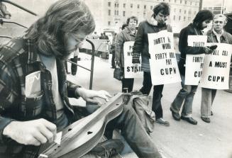 Striking Up The Music, Part-time post office worker John Heffernan 24, went to work today but only to play his dulcimer for the entertainment of strik(...)
