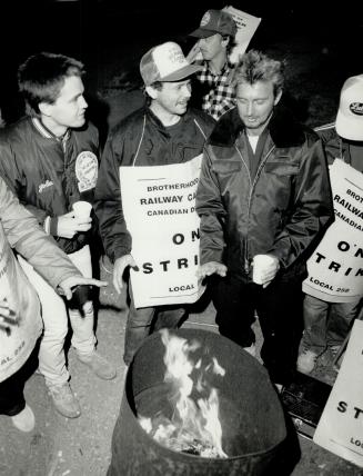 Long night: Pickets at CP Rail's Agincourt yard warm themselves around a barrel fire last night as they prepare for a long strike by 48,000 CN and CP rail workers across the country